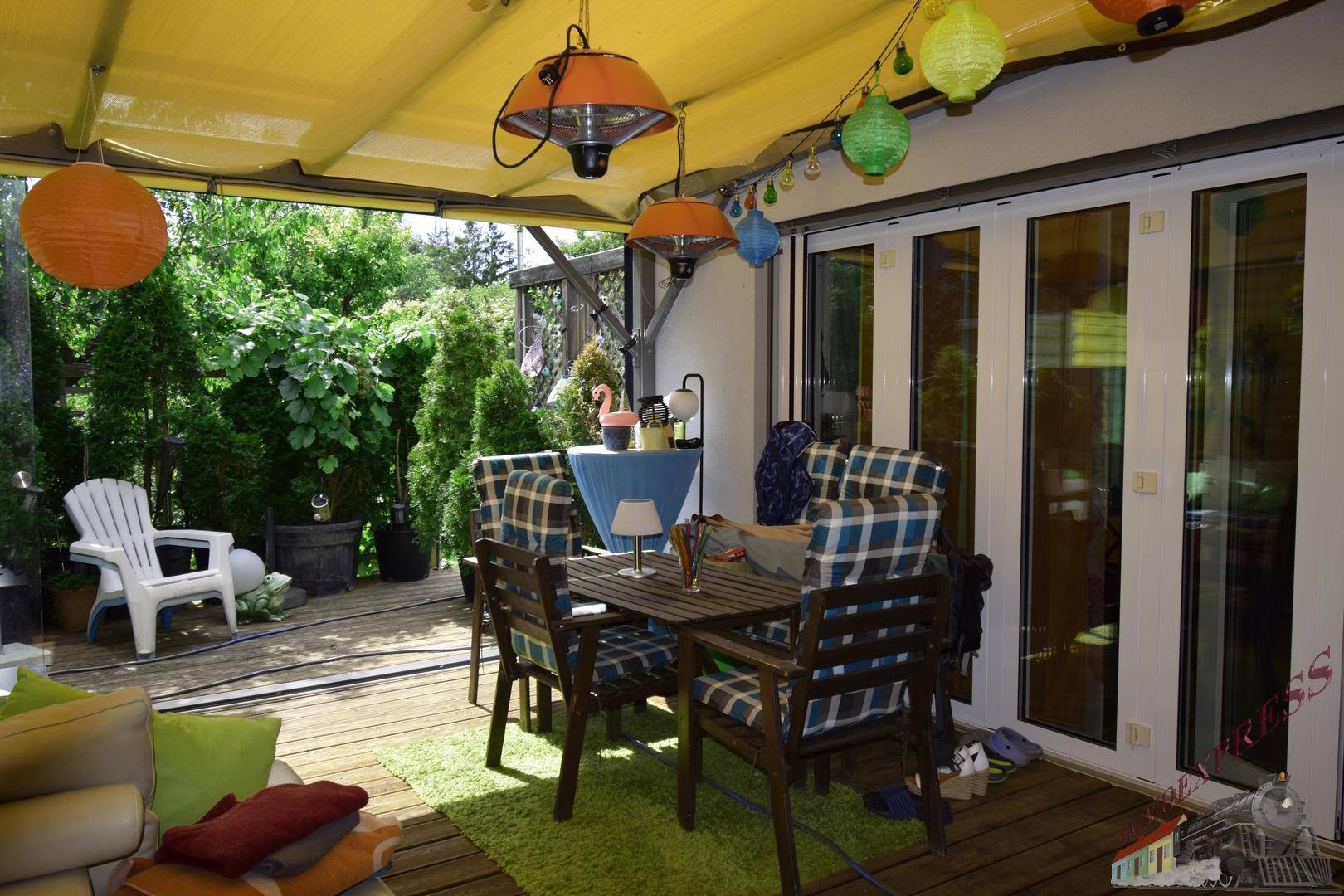 Geräumige überdachte Terrasse mit Esstisch, Lounge-Bereich und Zugang zum Garten.