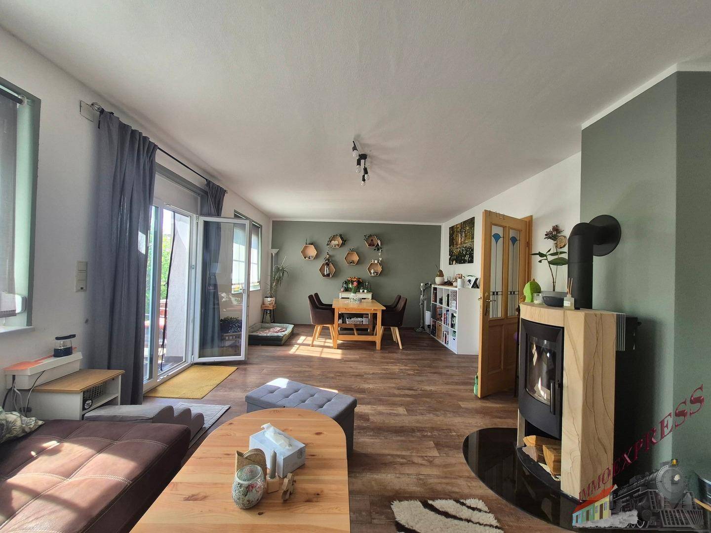 Geräumiger Wohn-Essbereich mit Kaminofen, Holzboden und Zugang zur Terrasse.