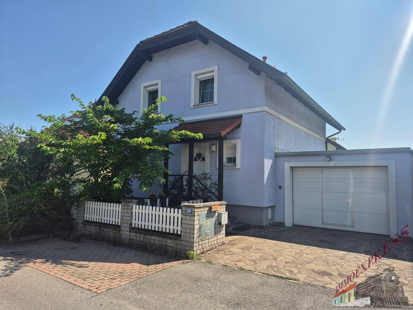 Vorderansicht des Einfamilienhauses mit Garage, gepflasterter Einfahrt und einem kleinen Vorgarten.