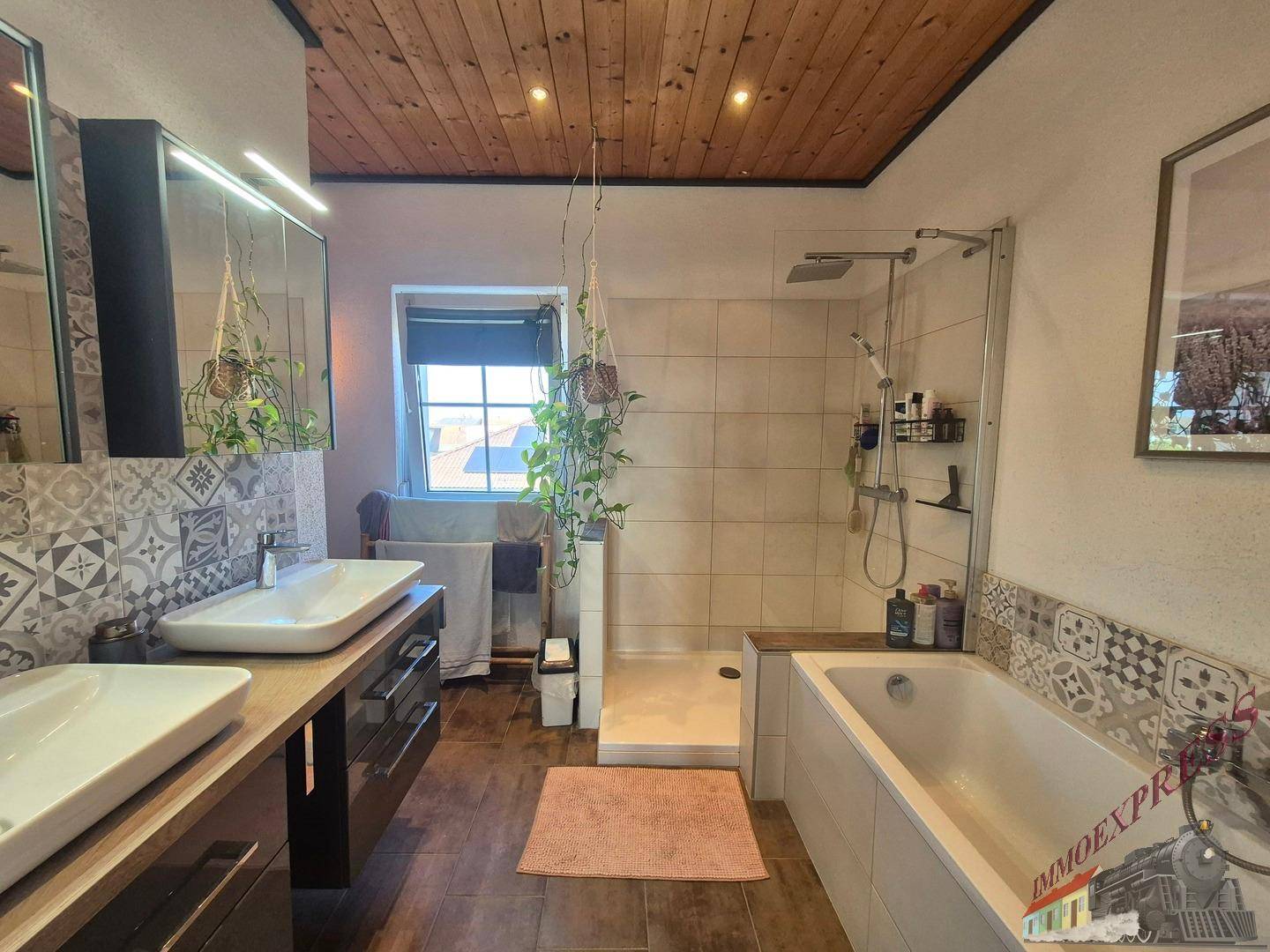 Modernes Badezimmer mit Doppelwaschbecken, Badewanne, Dusche und Holzdecke.
