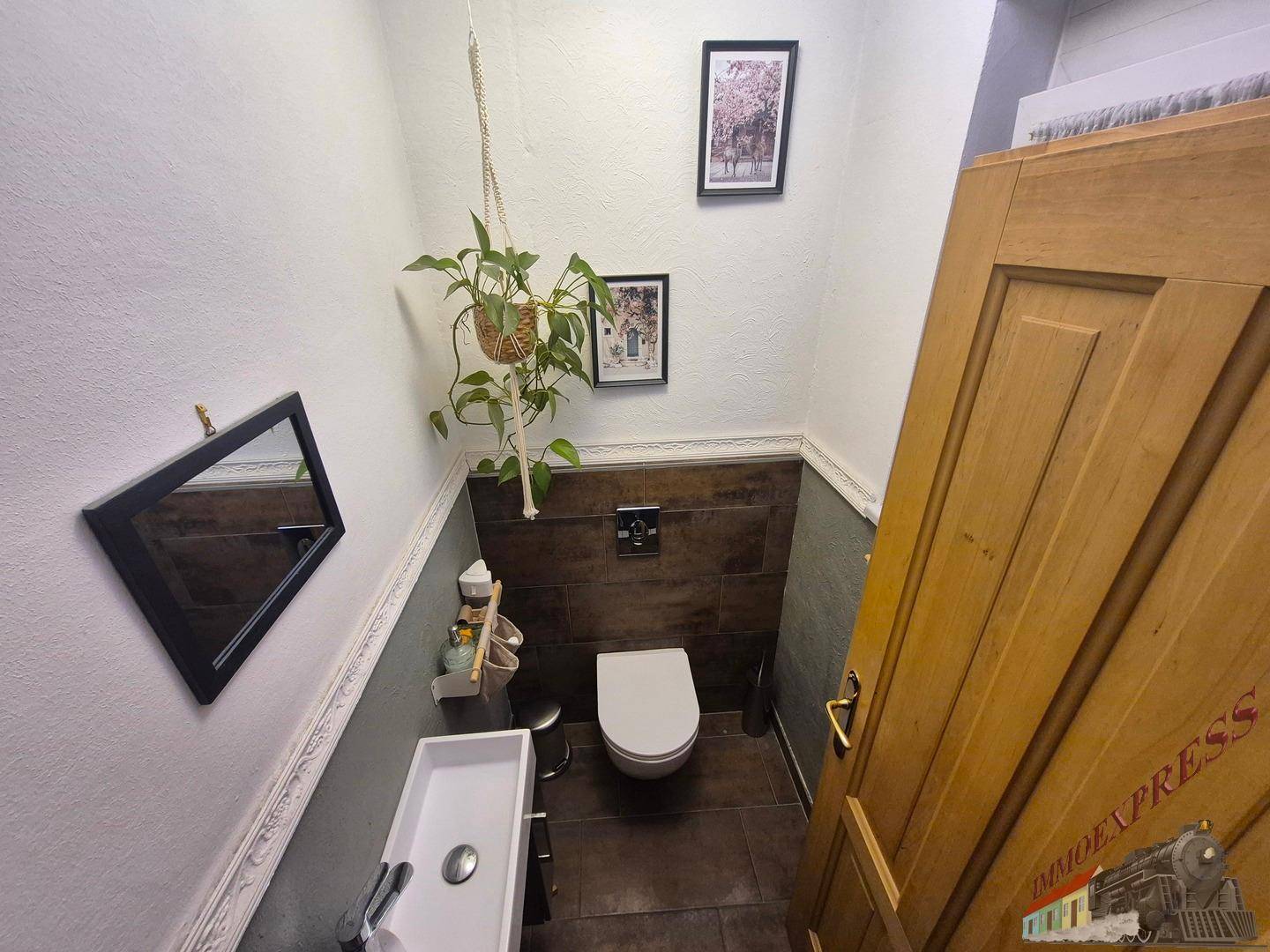 Kleines Gäste-WC mit modernem Waschbecken, Wand-WC und dunklen Fliesen.