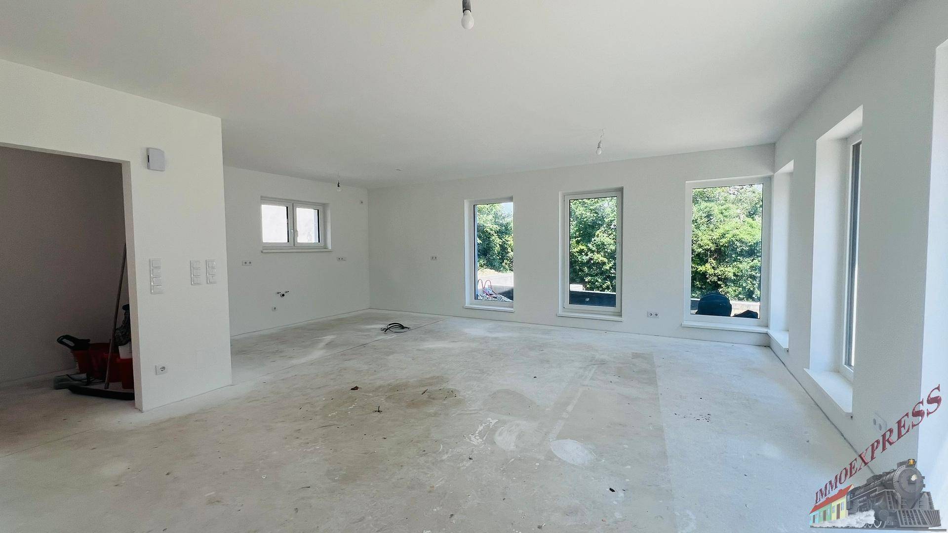 Heller, weitläufiger Raum im Neubau mit vielen Fenstern, die einen schönen Blick ins Grüne bieten.