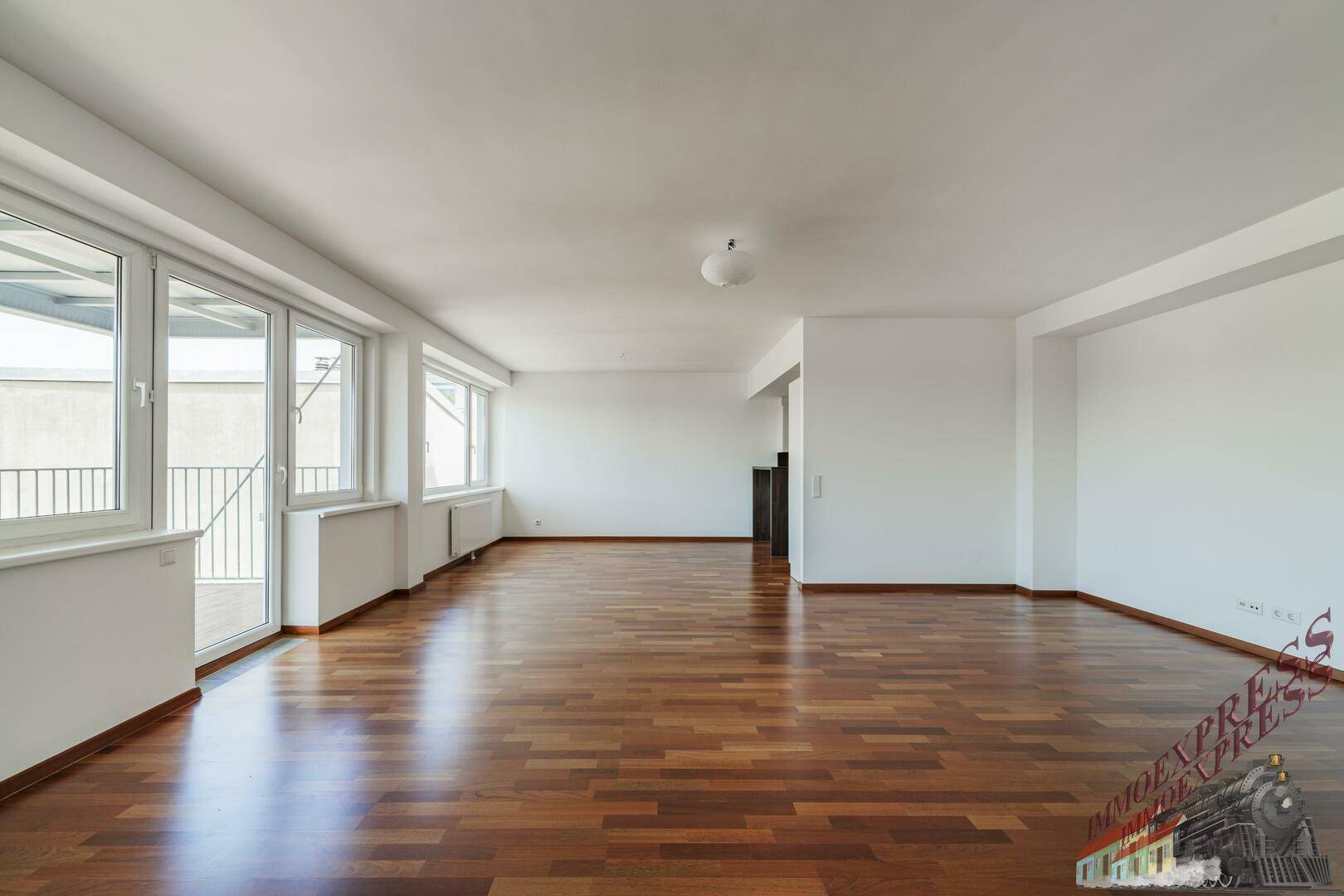 Lichtdurchfluteter Wohnbereich mit elegantem Parkettboden und einer Fensterfront, die viel Helligkeit spendet.