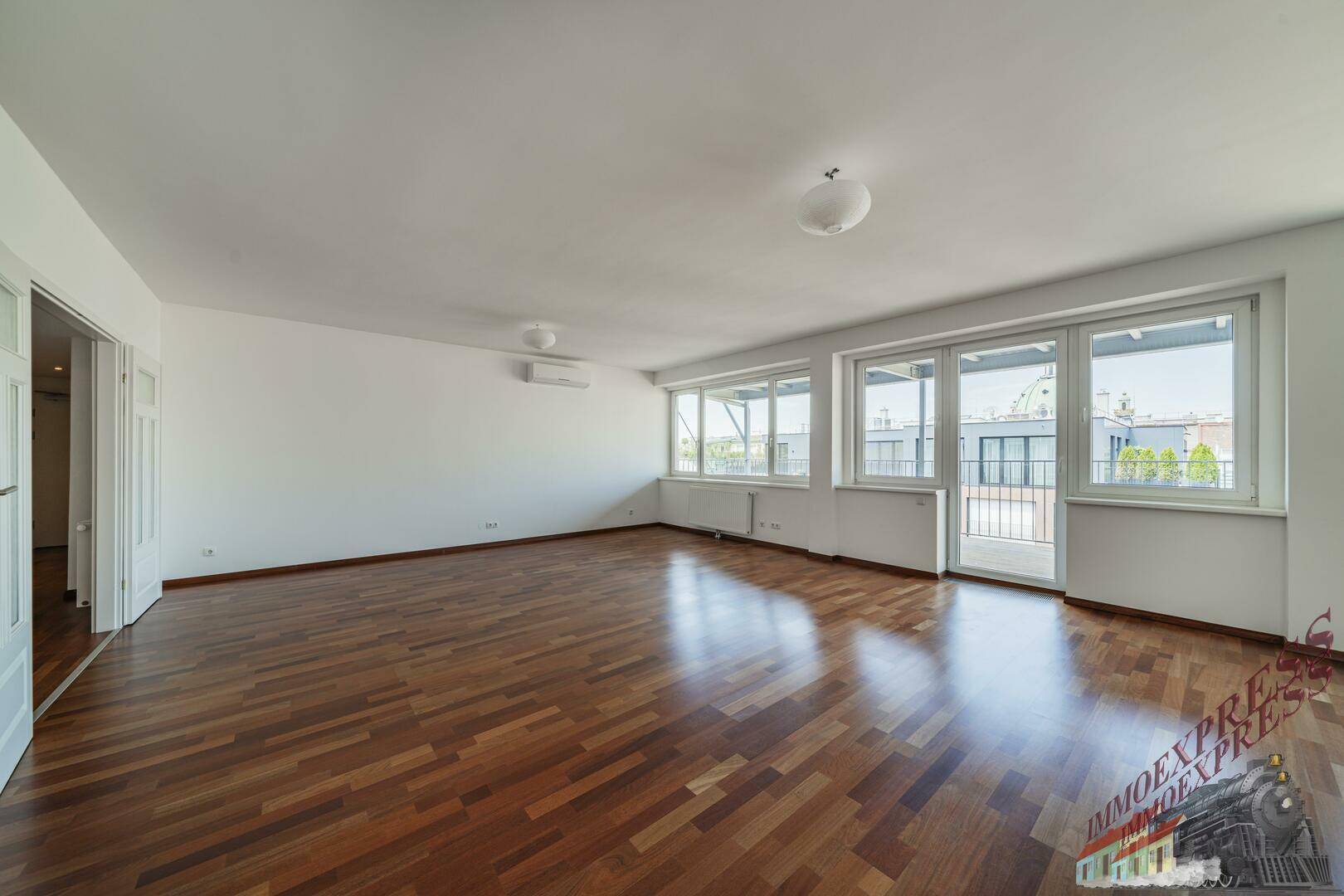 Helles und geräumiges Wohnzimmer mit Parkettboden und Zugang zu einem Balkon.