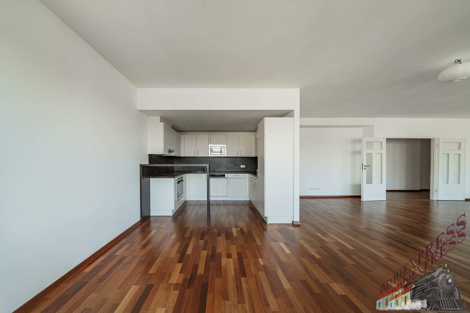 Moderne Einbauküche mit weißen Schränken und dunkler Arbeitsplatte, offen zum Wohnbereich.