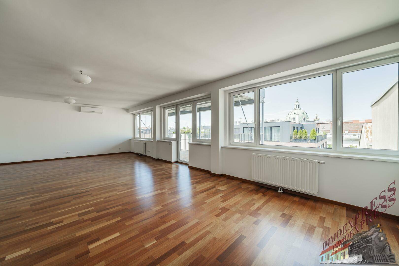 Helles und geräumiges Wohnzimmer mit Parkettboden, Klimaanlage und weitem Ausblick über die Stadt.