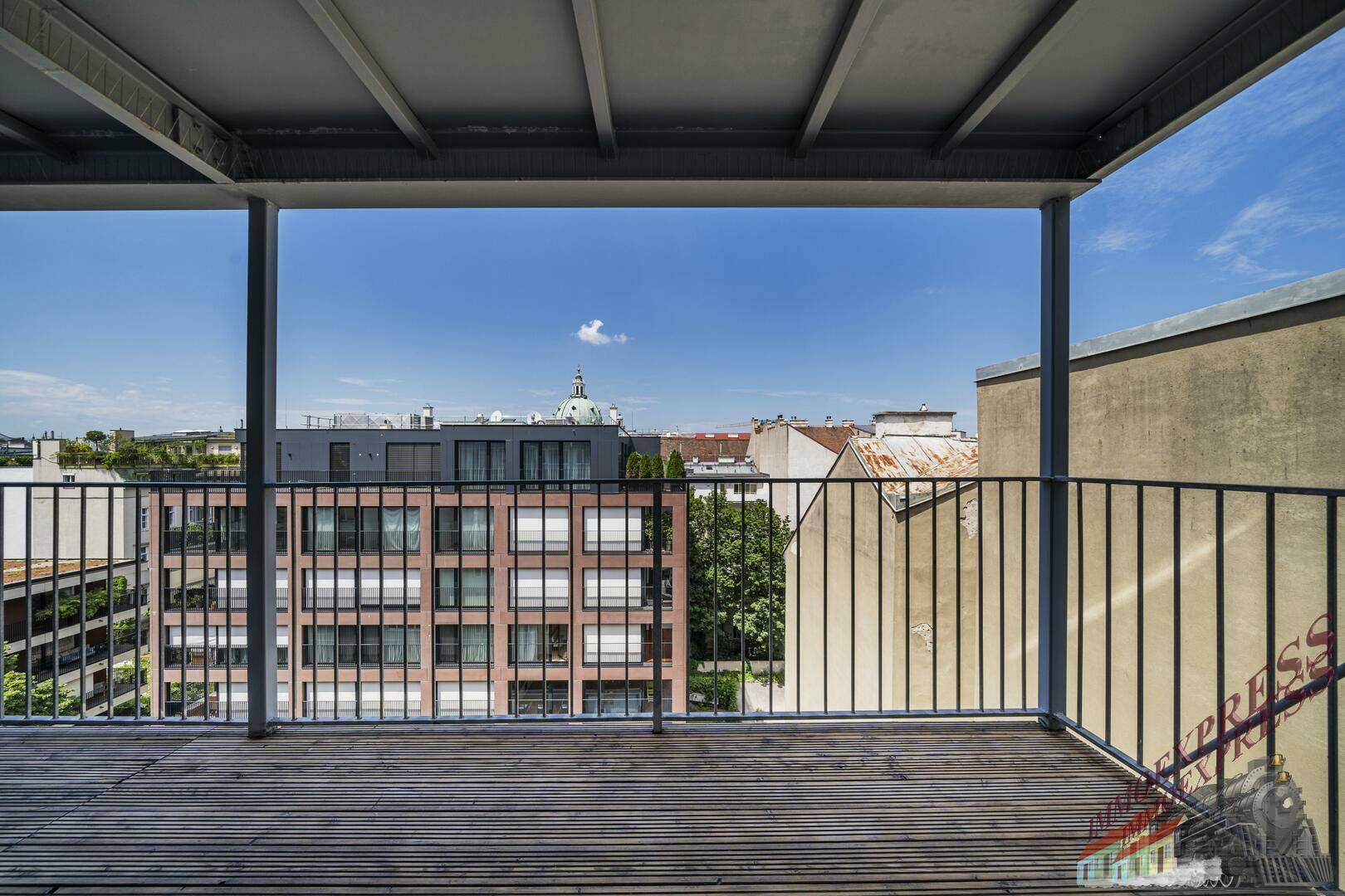 Balkon mit Holzboden und weitem Blick über die Stadt und umliegende Gebäude.