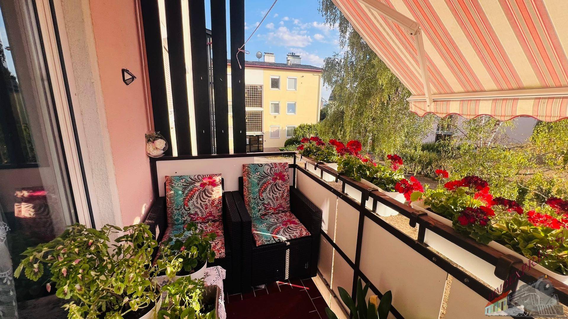 Möblierter Balkon mit bequemen Stühlen und Blumenkästen, bietet einen Blick auf die Umgebung.