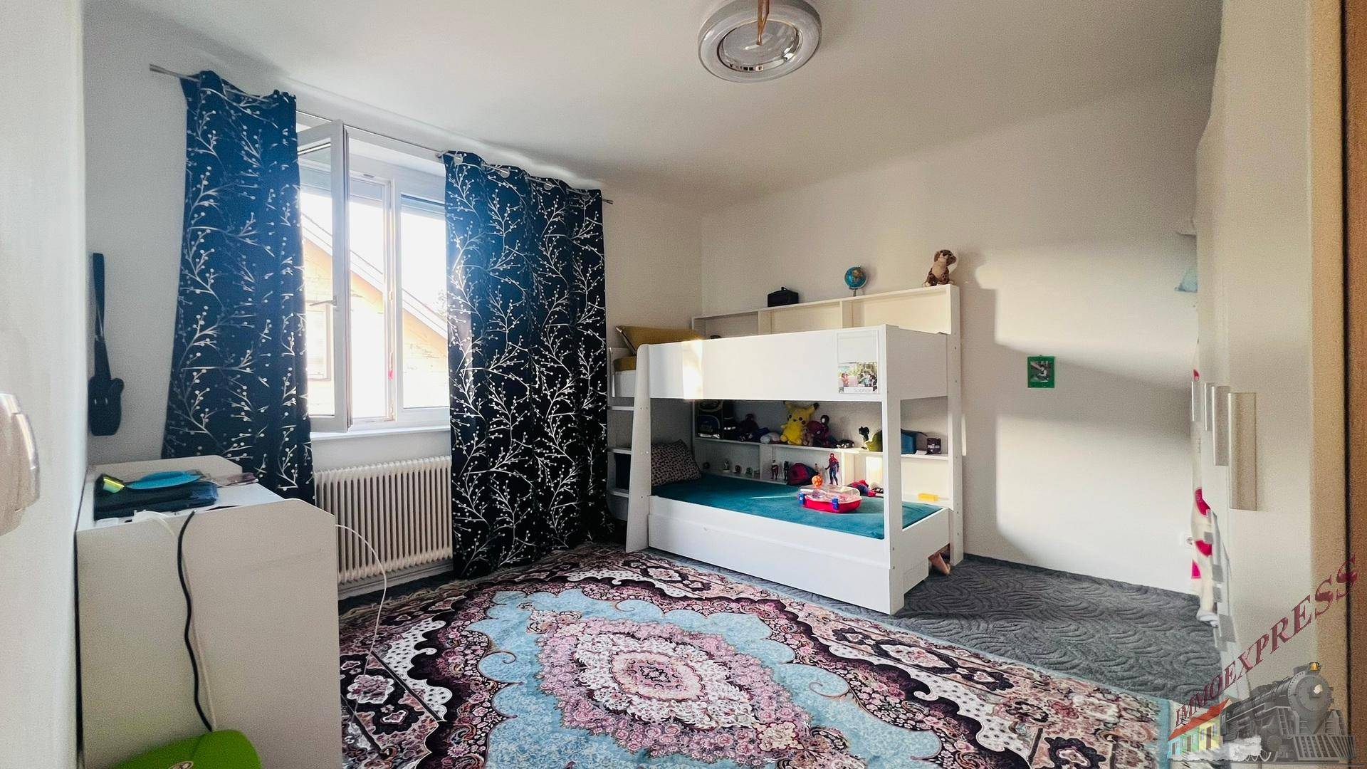 Kinderzimmer mit Etagenbett, Schreibtisch und farbenfrohem Teppich, ideal für Geschwister.