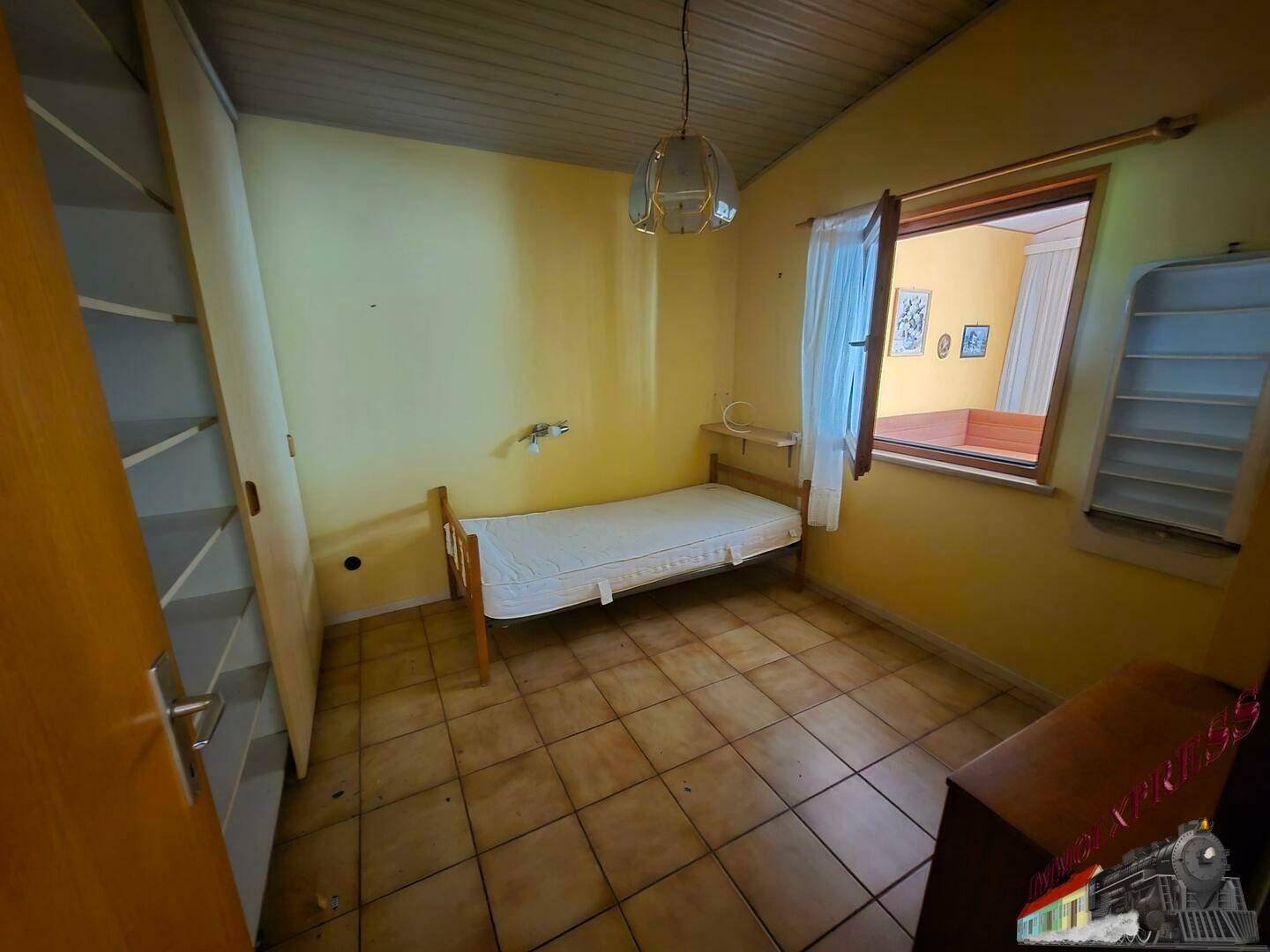 Helles Schlafzimmer mit Einzelbett, gelben Wänden und praktischem Kleiderschrank.