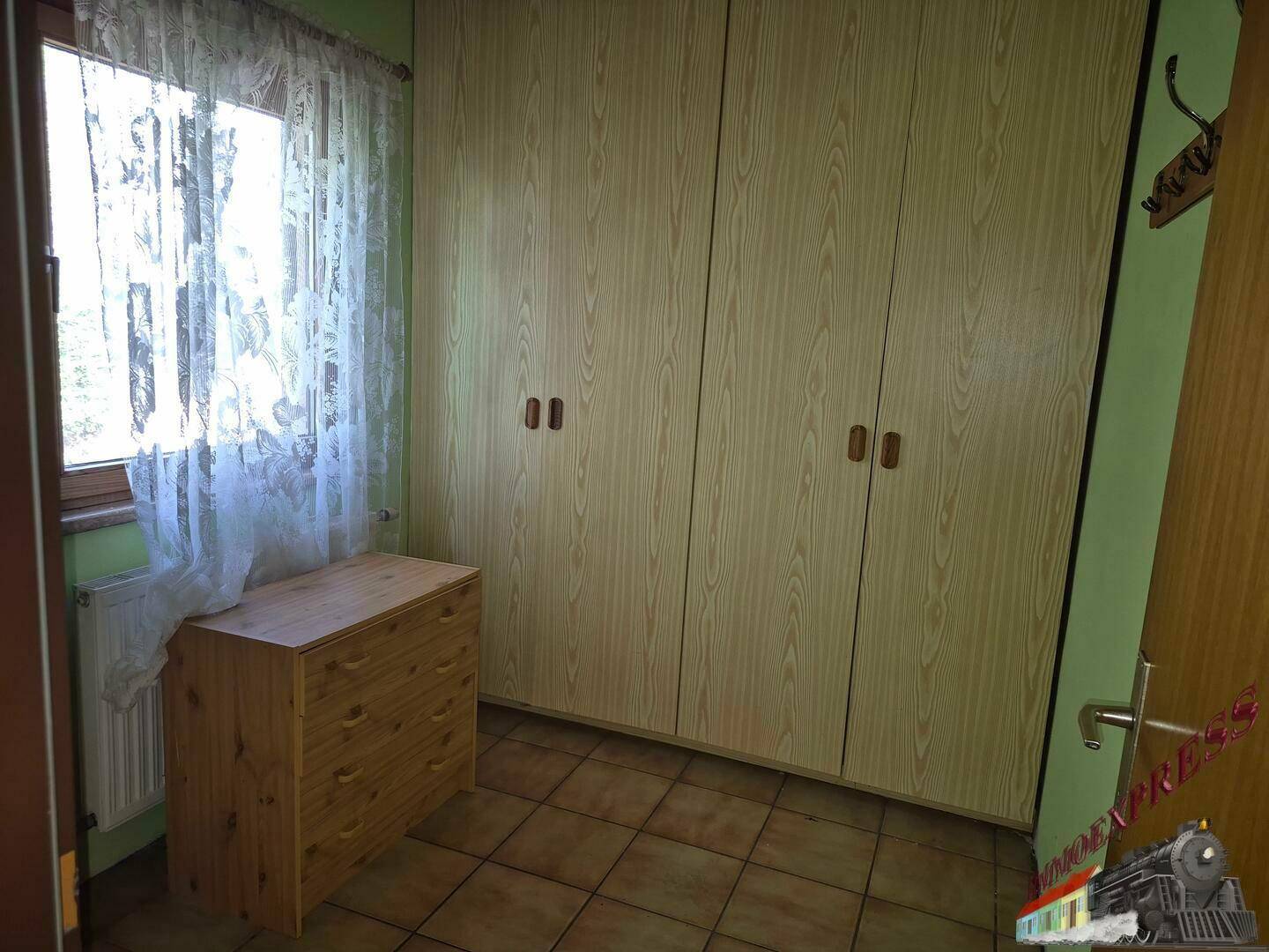 Schlafzimmer mit grünen Wänden, Fenster, Heizkörper und Einbauschränken.
