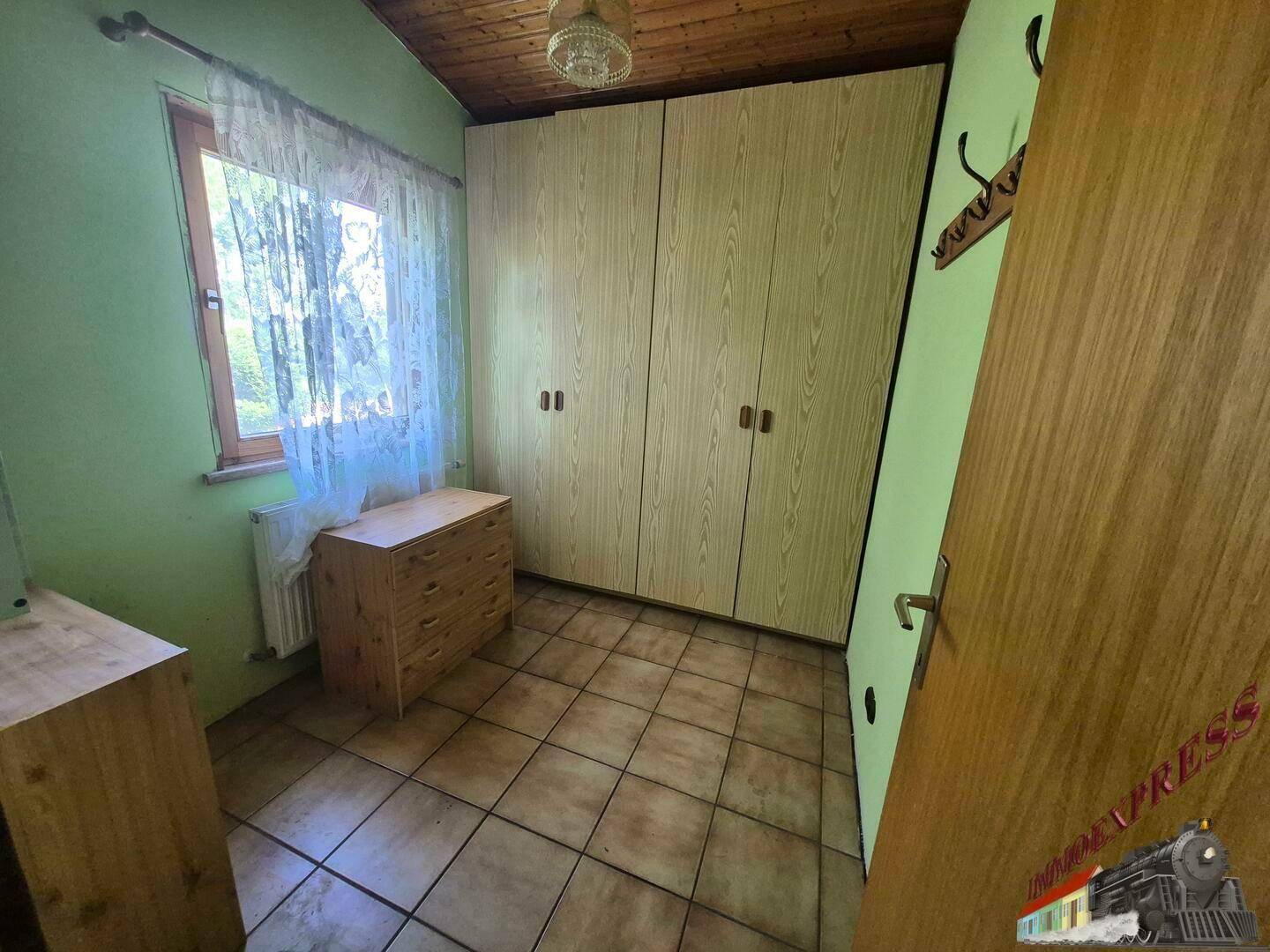 Gemütliches Schlafzimmer mit grünen Wänden, Fenster und geräumigen Einbauschränken.