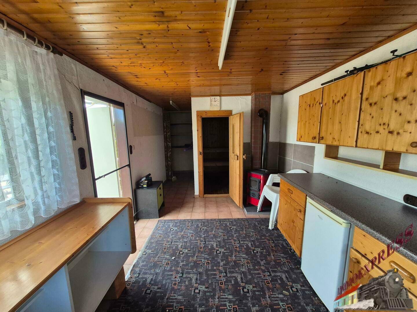 Übergangsbereich mit Blick in die Sauna, Holzofen und angrenzender Küchenzeile.