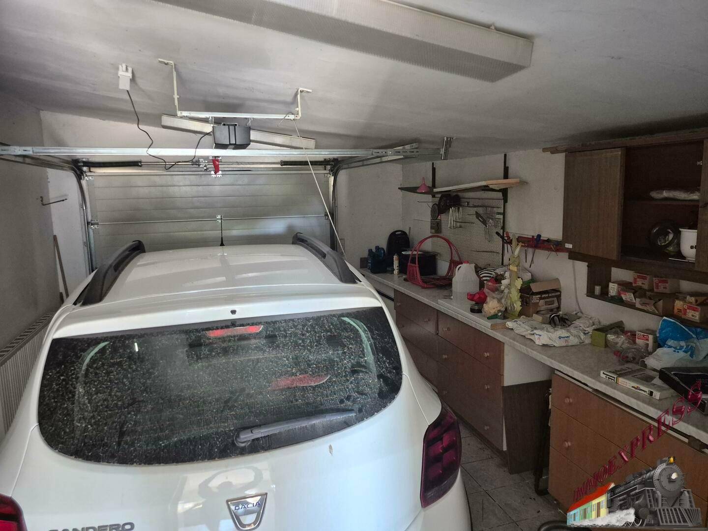 Geräumige Garage mit einem geparkten Auto und Regalen für Werkzeuge und Lagerung.