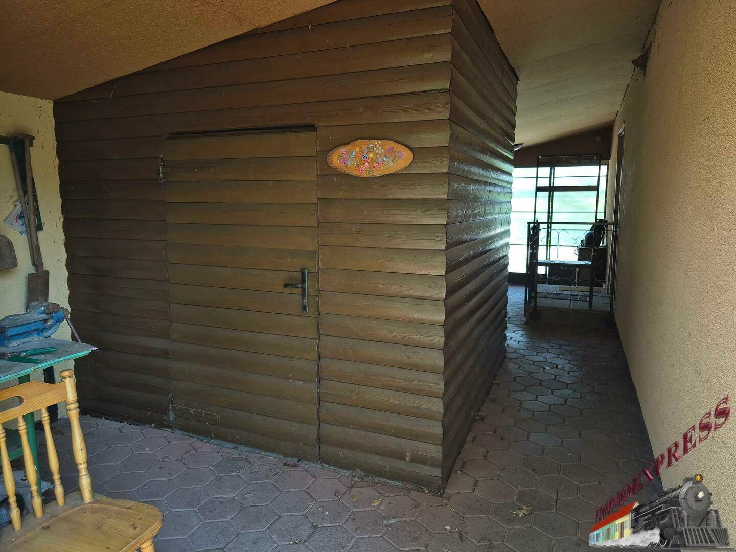 Überdachter Außenbereich mit einem Holzschuppen und gefliestem Boden, ideal für Lagerung.