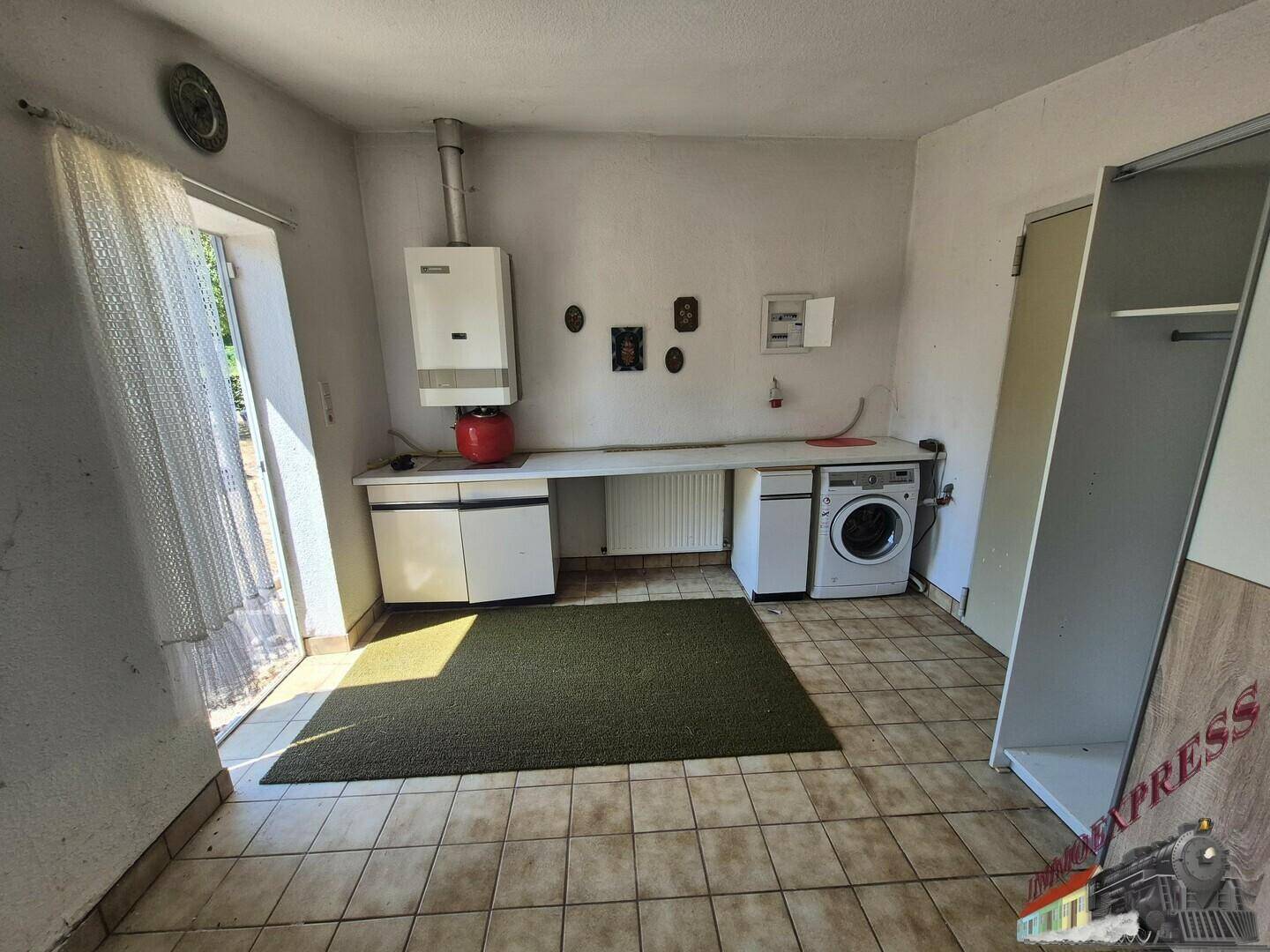 Heller Hauswirtschaftsraum mit Waschmaschine, Warmwasserbereiter und Zugang nach draußen.