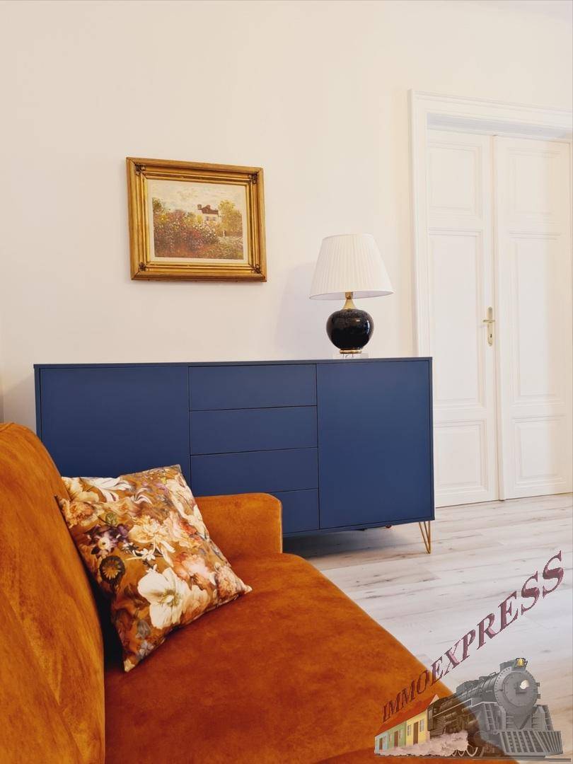 Detailansicht des Wohnbereichs mit bequemer orangefarbener Couch und stilvollem Sideboard.