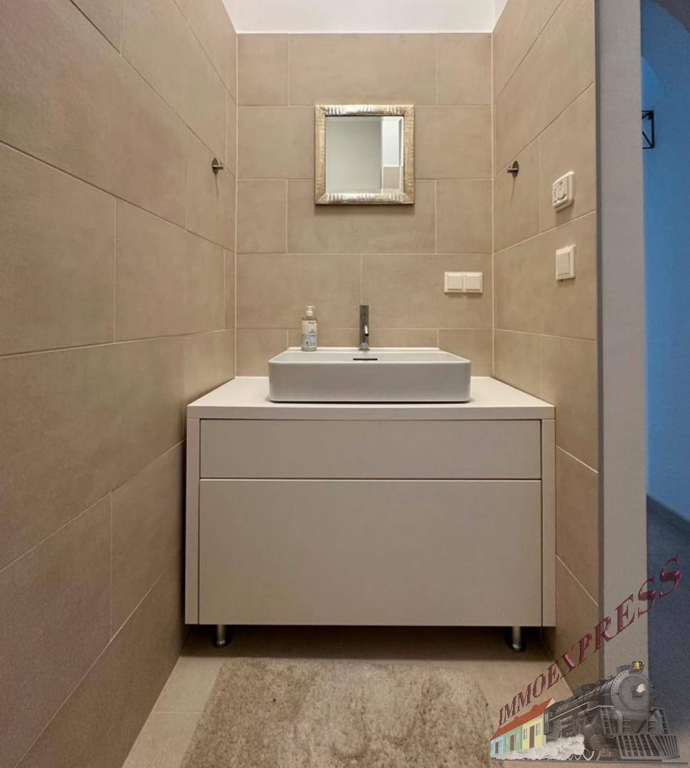 Modernes Badezimmer mit stilvollem Waschtisch, Aufsatzwaschbecken und großen Fliesen.