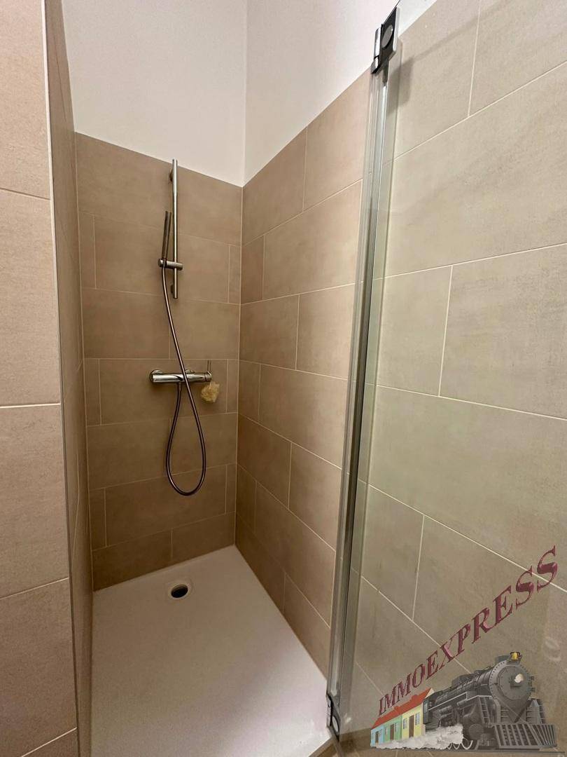 Geräumige Dusche mit modernen Fliesen und Glasabtrennung, barrierefrei gestaltet.