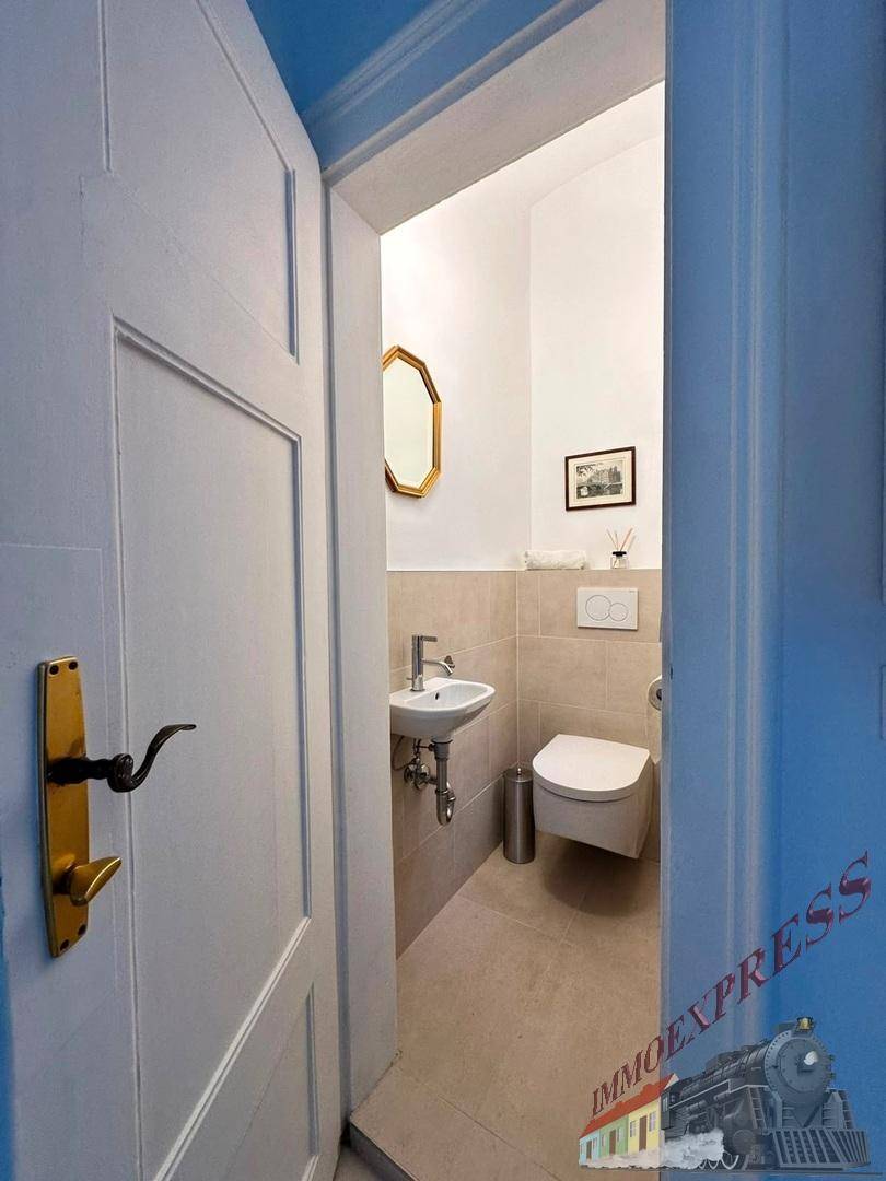 Kleines Gäste-WC mit wandhängendem WC, Handwaschbecken und modernen Fliesen.