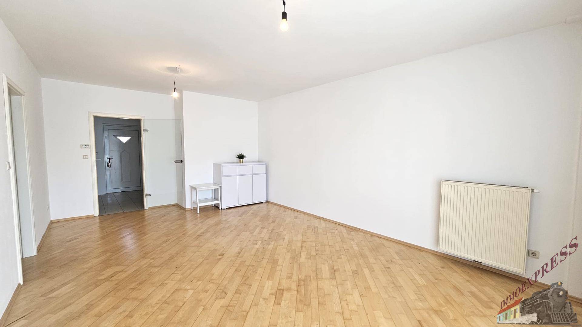Heller Eingangsbereich mit Parkettboden und einer weißen Kommode.