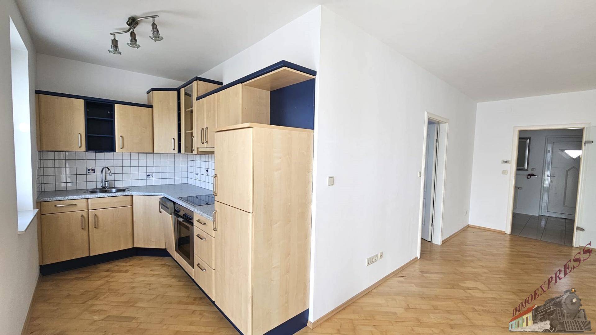Einbauküche mit hellen Holzfronten, blauen Akzenten und Fliesenboden.