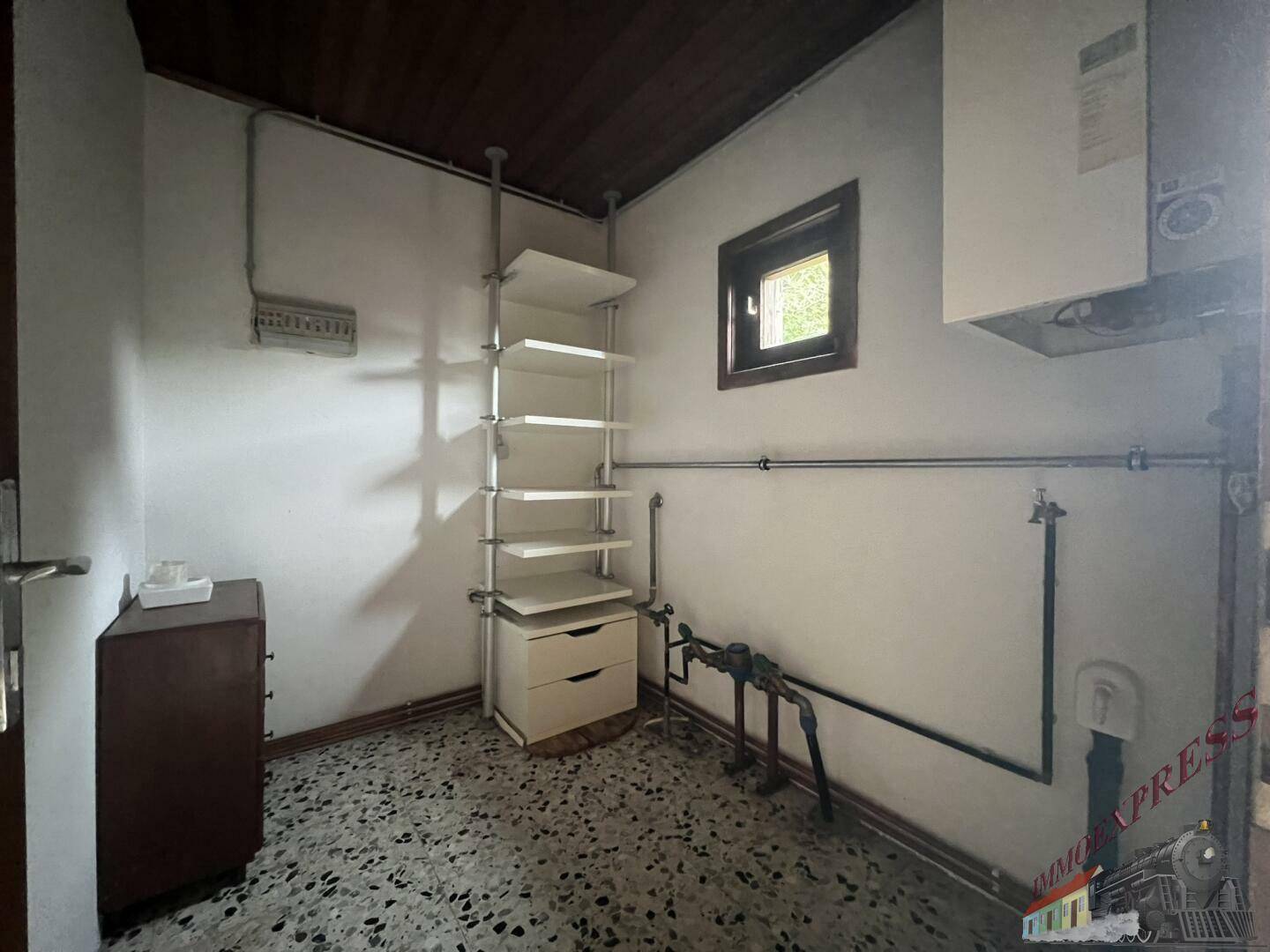 Praktischer Hauswirtschaftsraum mit Regalen, Warmwasserbereiter und Fliesenboden.