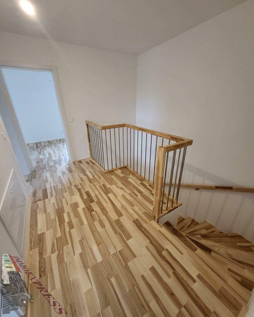 Treppenaufgang mit Holzstufen und modernem Geländer, führt zu den oberen Zimmern.