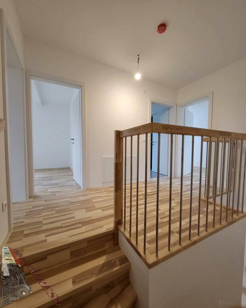 Heller Flur im Obergeschoss mit Laminatboden und Holzgeländer.