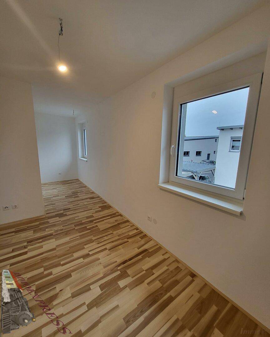 Geräumiges Schlafzimmer mit Laminatboden und zwei Fenstern für viel Licht.