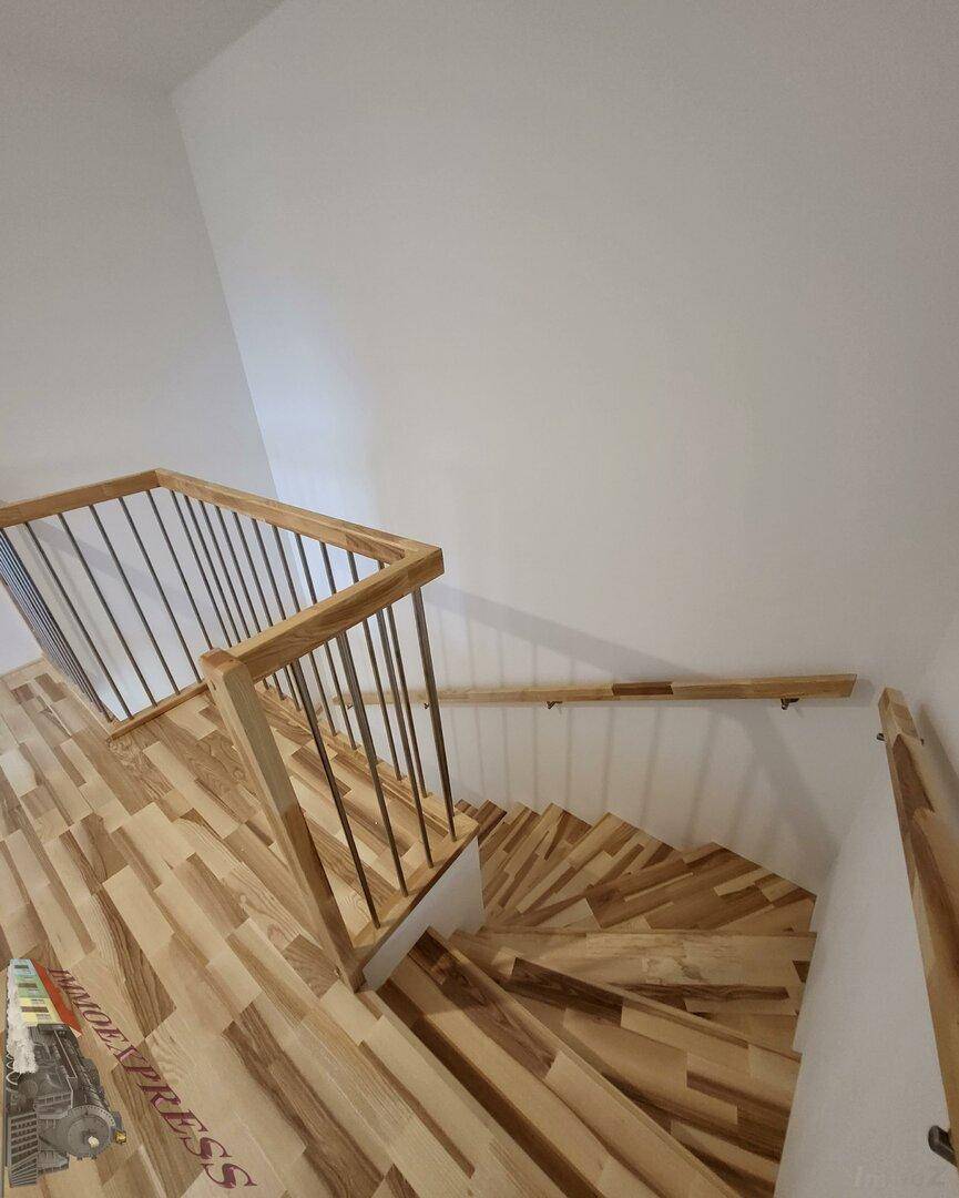 Wendeltreppe mit Holzstufen und modernem Geländer, verbindet die Stockwerke.