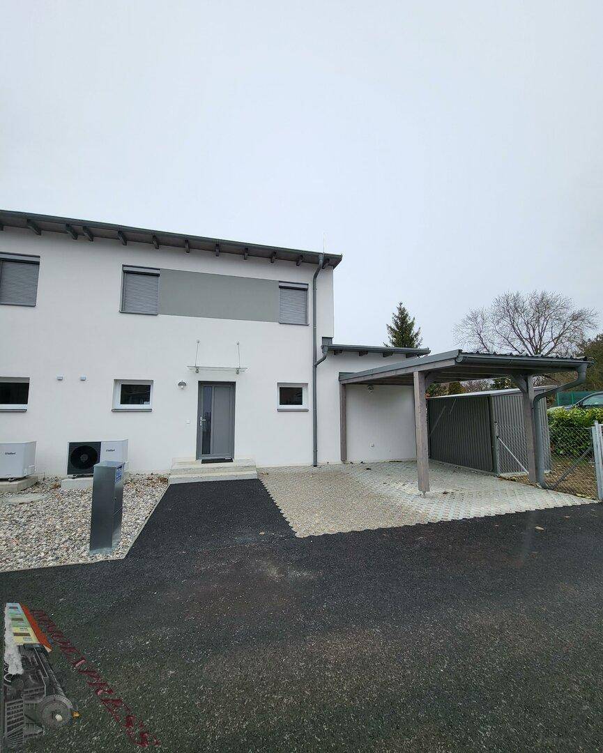 Vorderansicht der Doppelhaushälfte mit Eingangsbereich, Carport und Stellplatz.