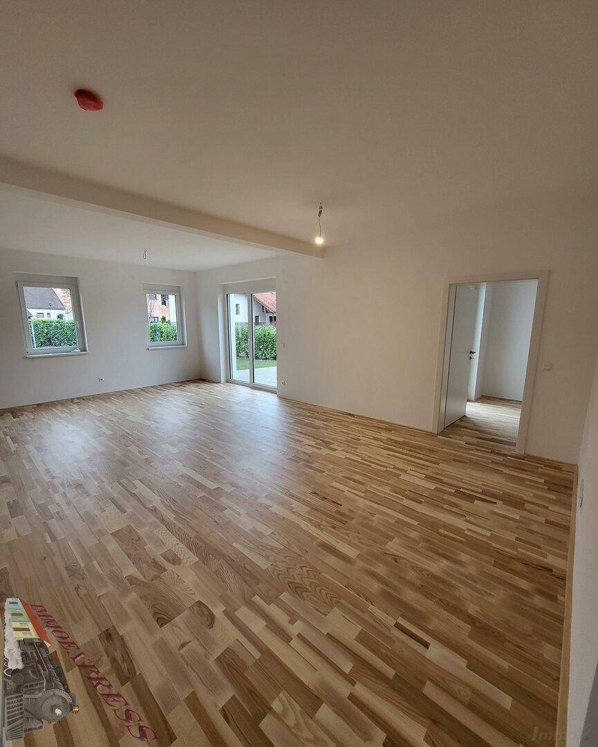 Heller Wohn- und Essbereich mit Laminatboden und Blick in den Garten.