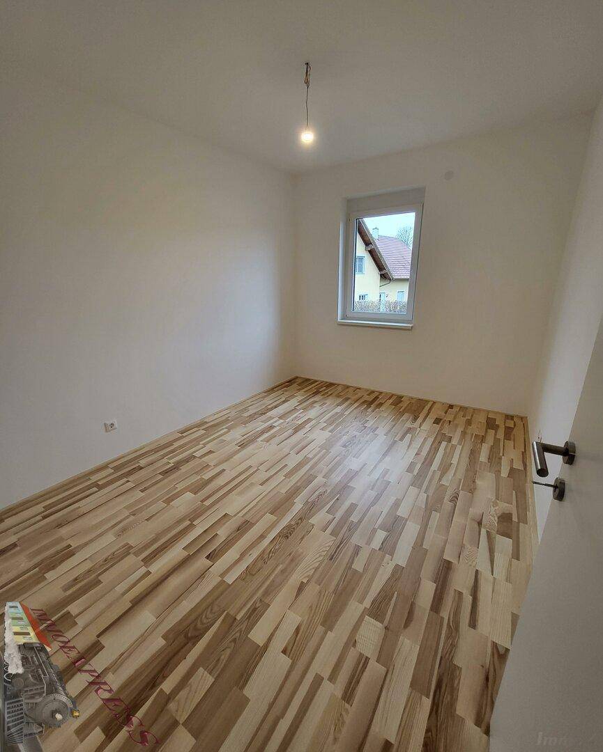 Gemütliches Schlafzimmer mit Laminatboden und einem Fenster für Tageslicht.