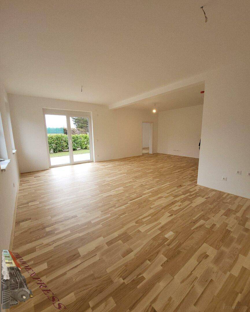 Geräumiger Wohnbereich mit hellem Laminatboden und Zugang zum Garten.