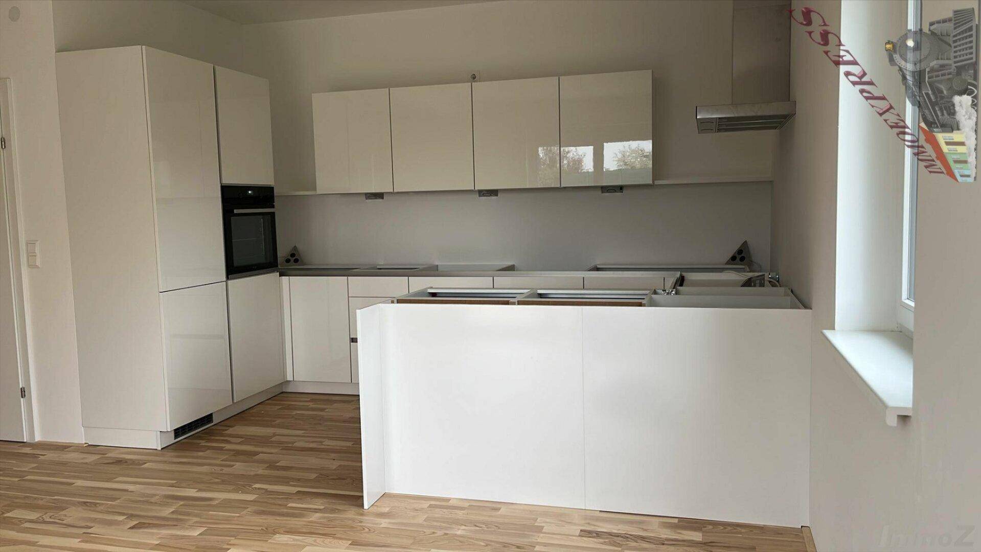 Moderne Einbauküche in Weiß mit Kochinsel und integrierten Geräten.