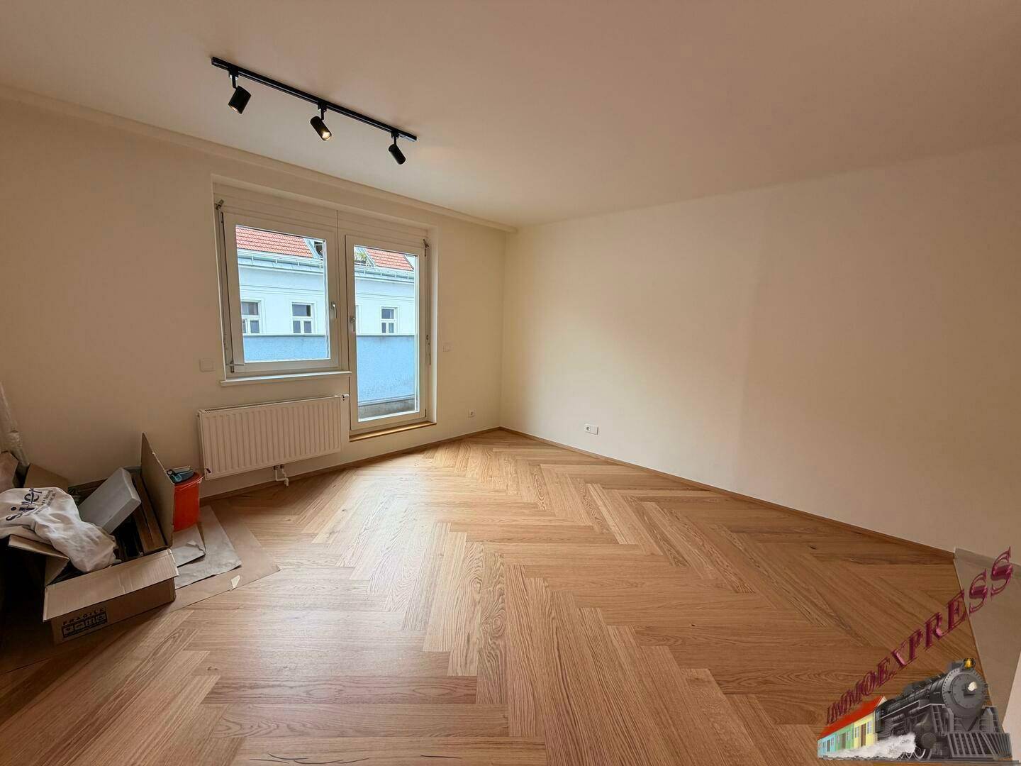 Geräumiger Wohnbereich mit neuem Fischgrätparkett und großem Fenster für viel Tageslicht.