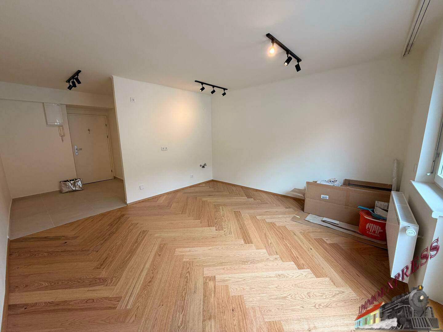 Heller, leerer Raum mit modernem Fischgrätparkett und weiß gestrichenen Wänden.