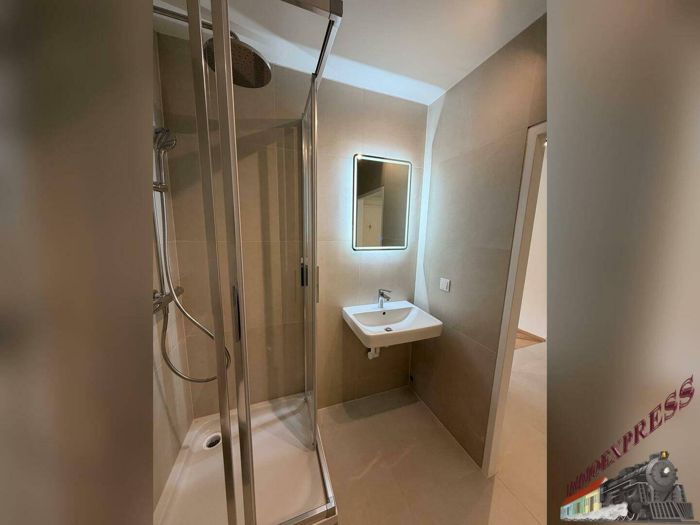 Helles Badezimmer mit Duschkabine, Waschbecken und beleuchtetem Spiegel in neutralen Farbtönen.