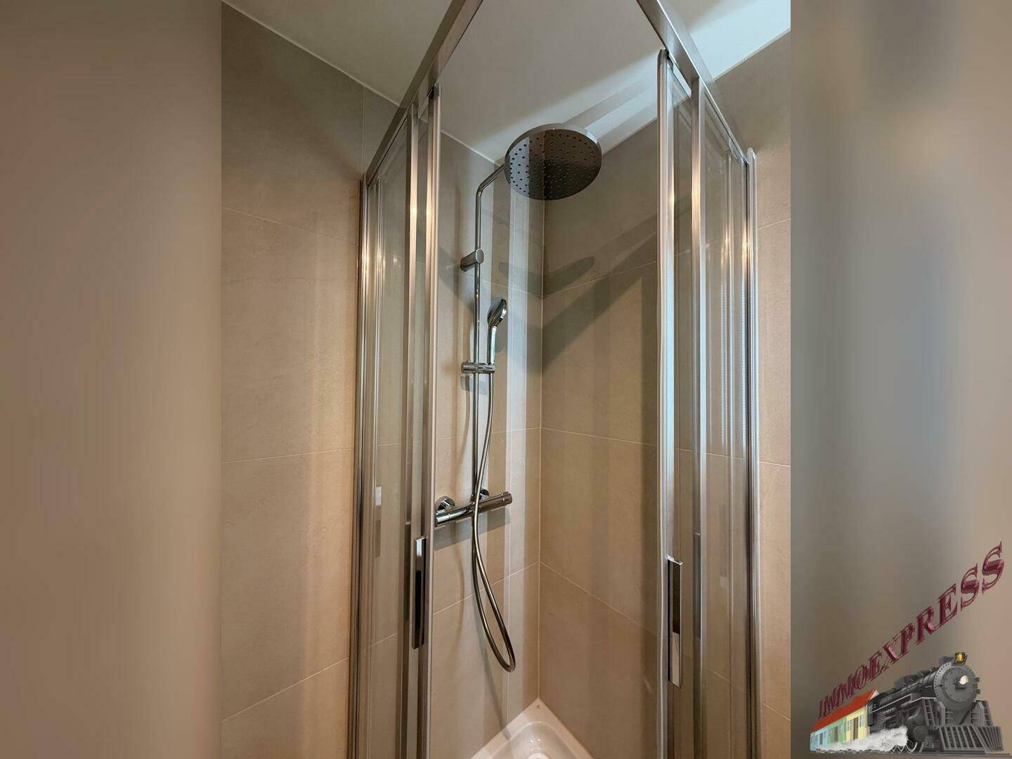Duschkabine mit moderner Regendusche und beigefarbenen Fliesen im Badezimmer.