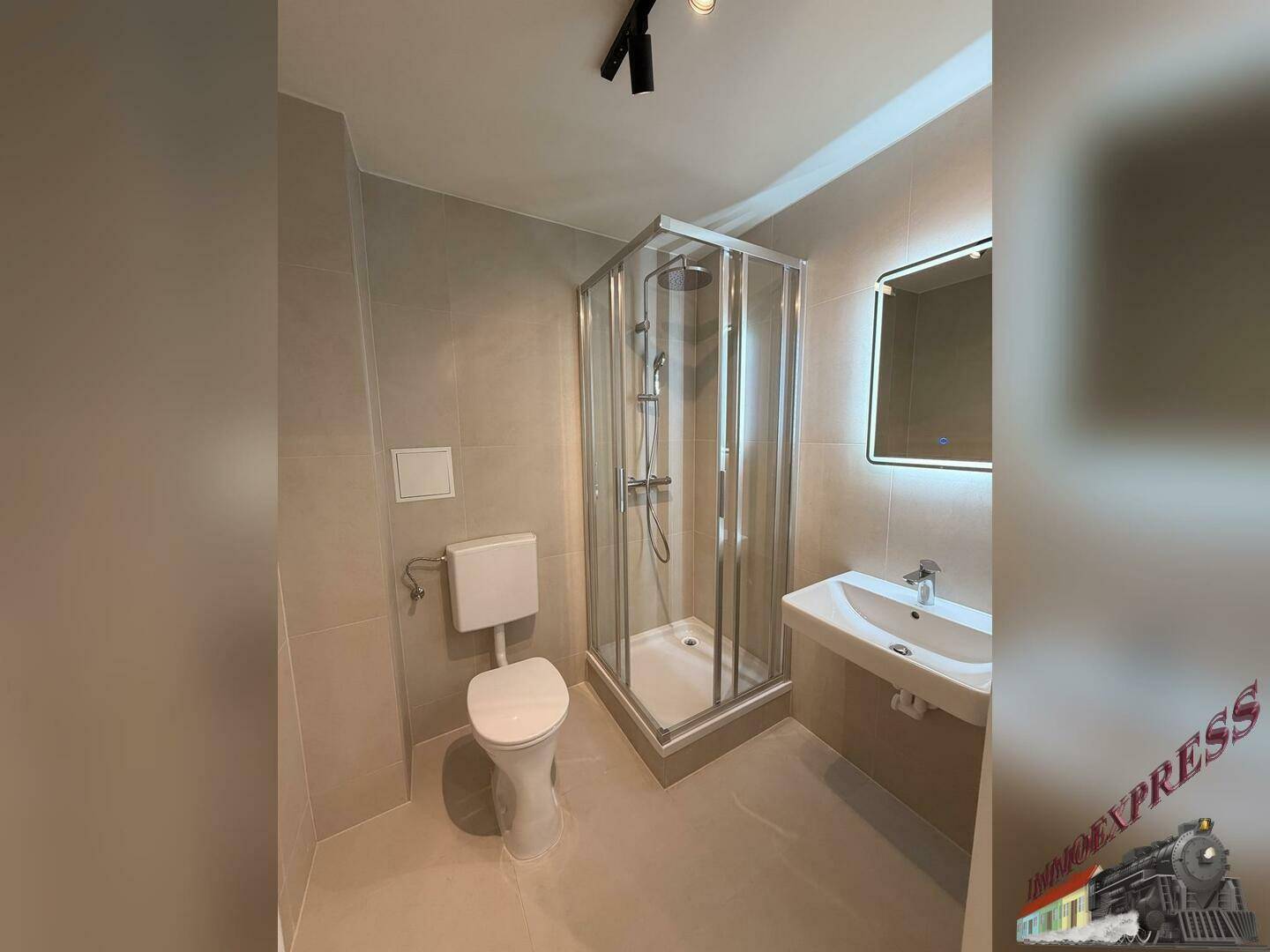 Modernes Badezimmer mit Duschkabine, WC, Waschbecken und beleuchtetem Spiegel.