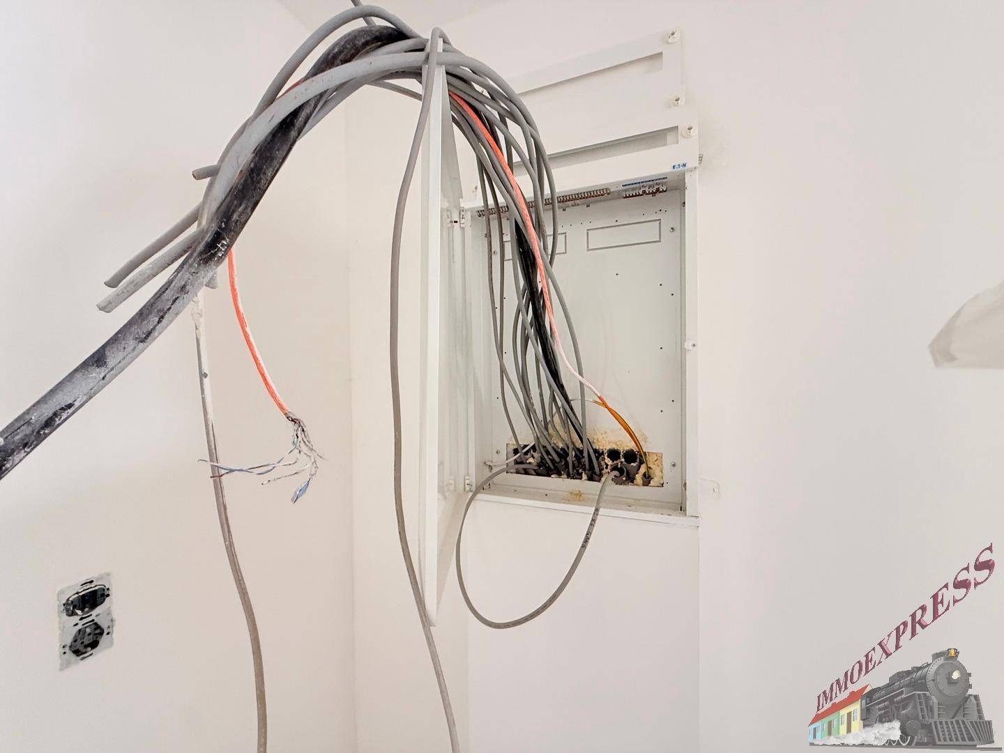 Offener Sicherungskasten mit Verkabelung im Rohbau, bereit für den Anschluss.