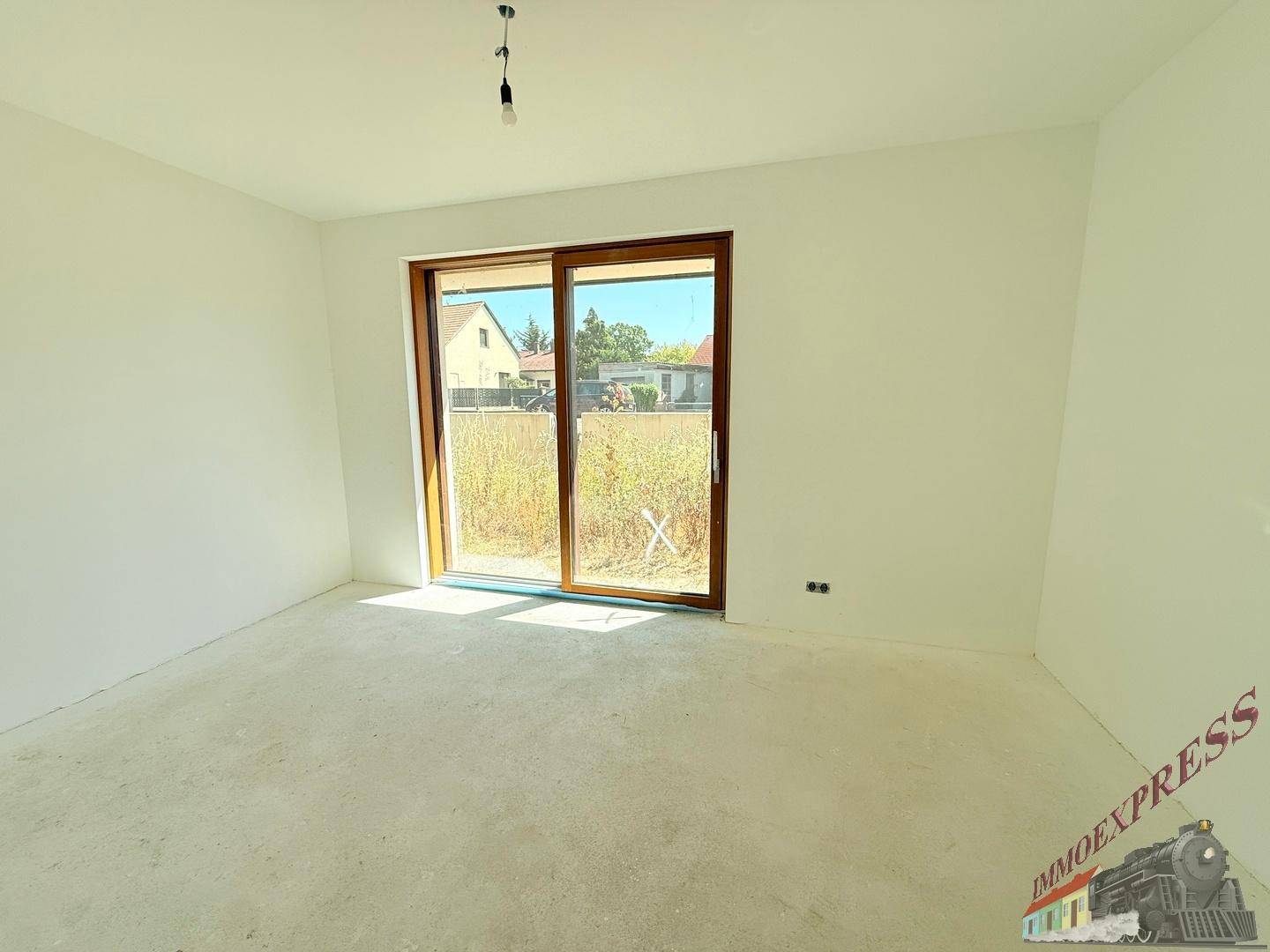 Helles Schlafzimmer im Rohbau mit großer Schiebetür und Blick auf die Umgebung.