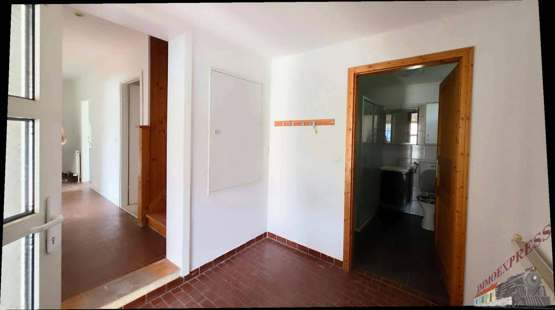 Eingangsbereich mit Fliesenboden, der zu einem Badezimmer und weiteren Räumen führt.