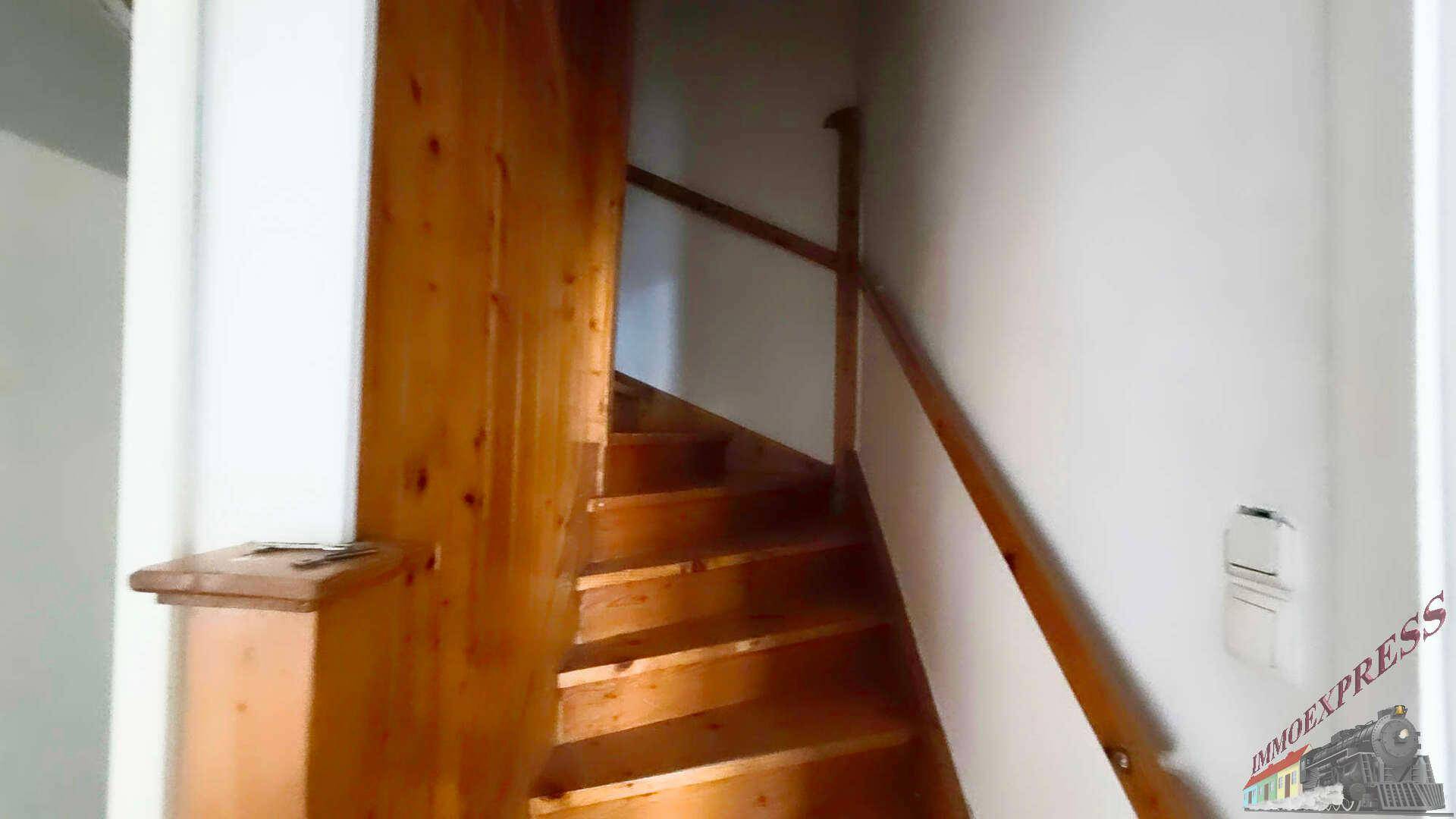 Holztreppe mit Geländer, die die verschiedenen Etagen des Hauses verbindet.