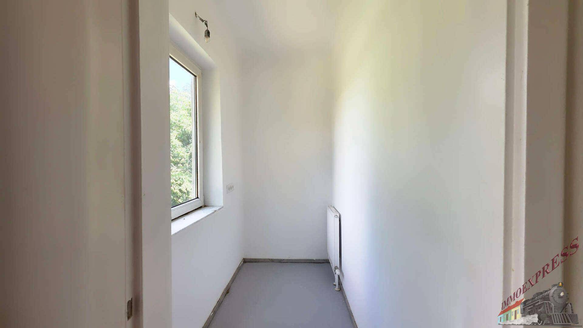 Kleiner, heller Raum mit einem Fenster, Heizkörper und schlichten weißen Wänden.