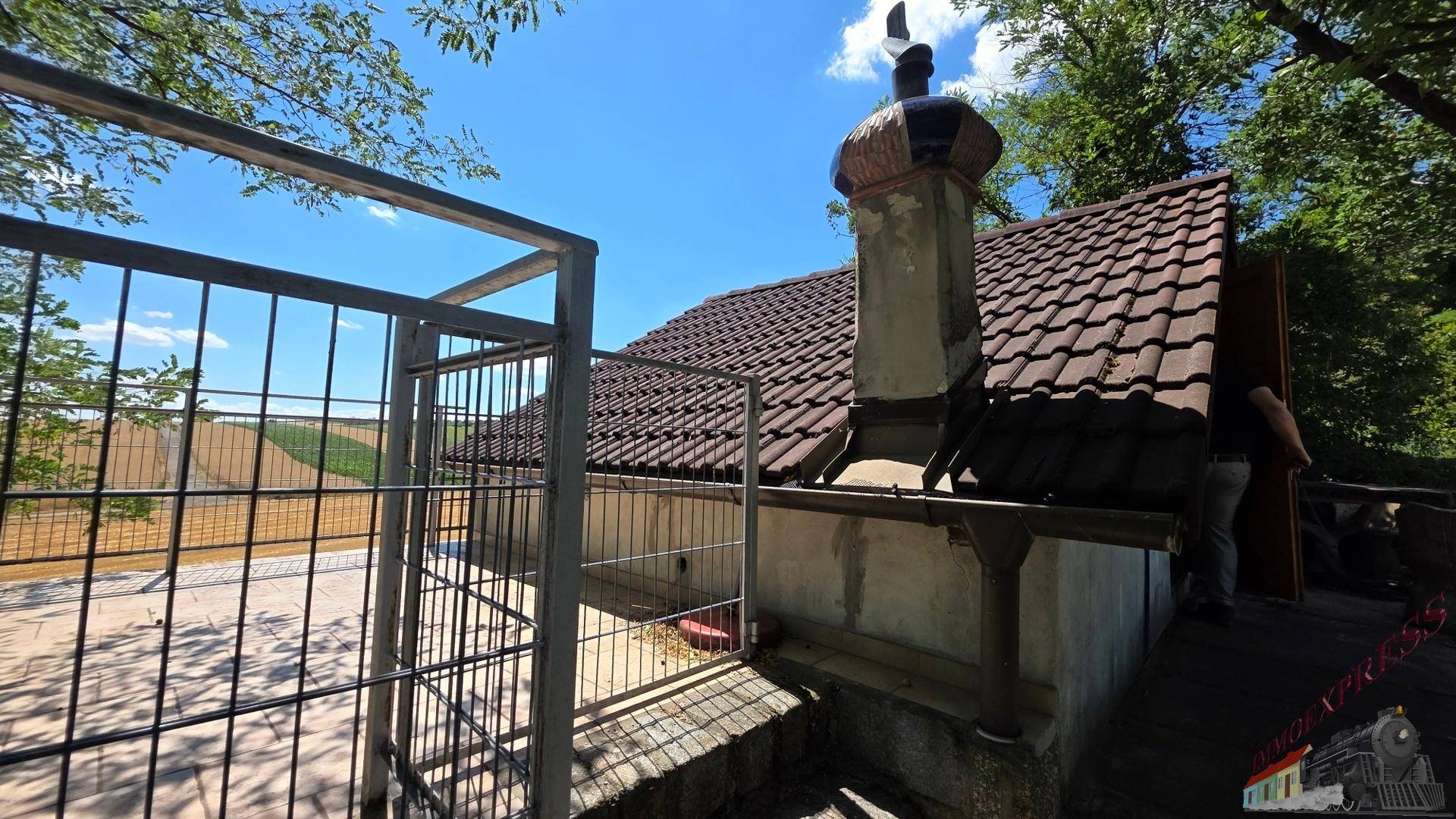 Detailansicht des Daches mit Schornstein und einem umzäunten Bereich im Freien.