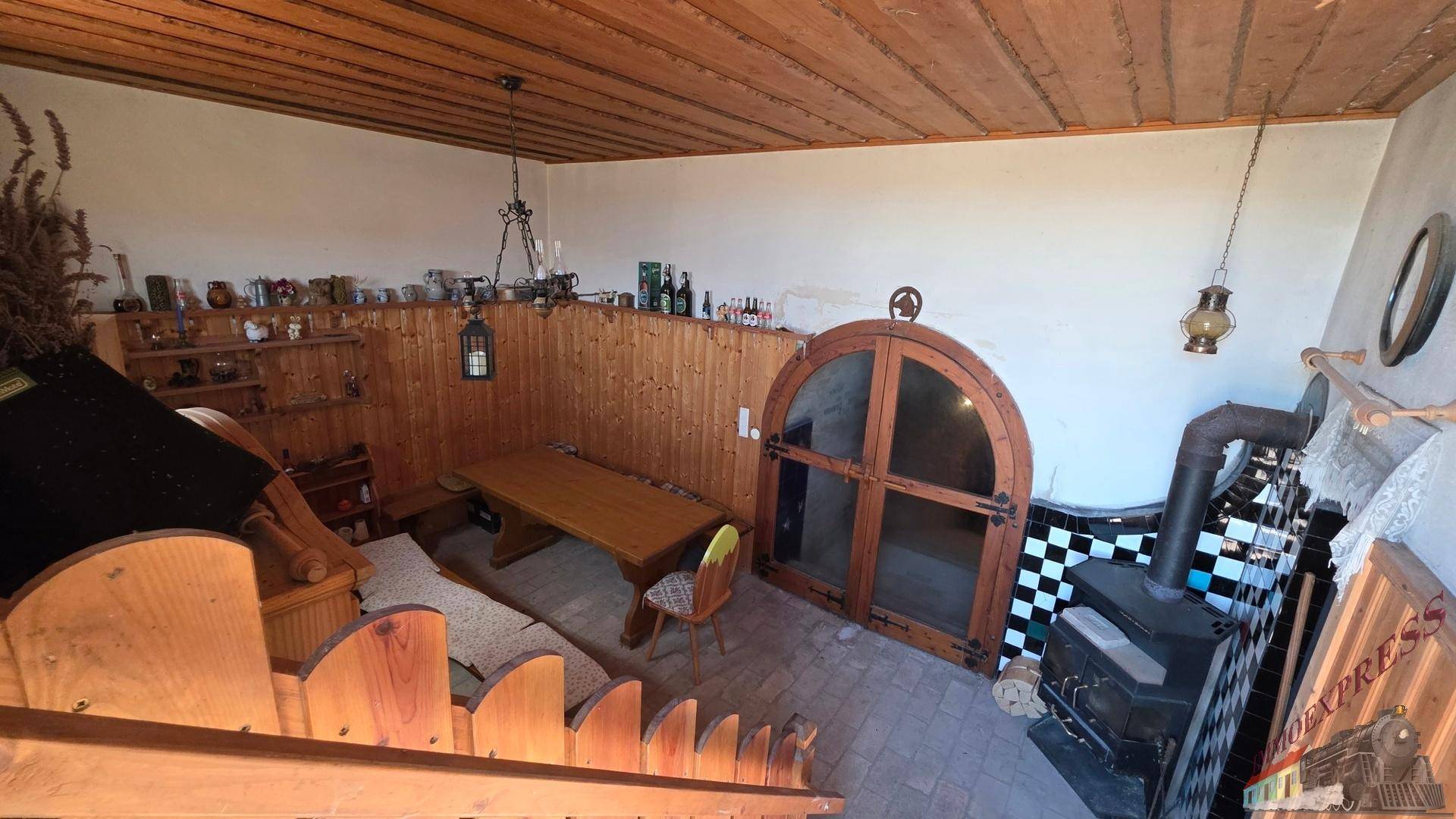Gemütlicher Wohnbereich mit Holzvertäfelung, Kaminofen und einer einzigartigen Rundbogentür.