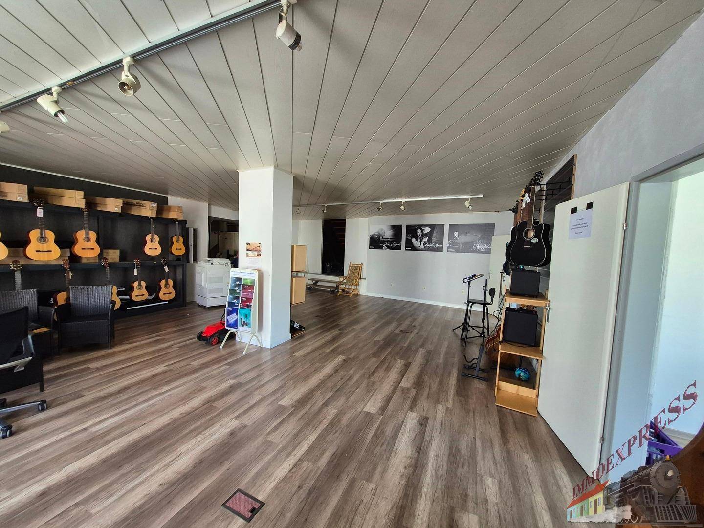 Großer offener Raum mit Laminatboden und Gitarrenausstellung, ideal für Musikliebhaber.