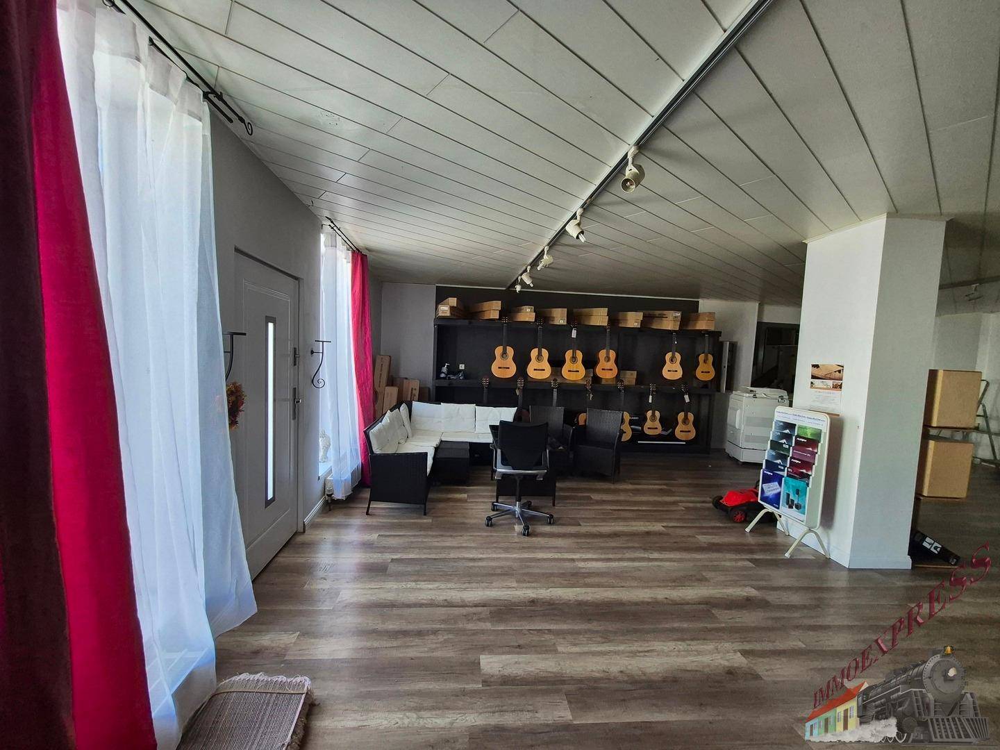 Heller Wohnbereich mit Laminatboden, bequemen Sofas und Musikinstrumenten, einladend und geräumig.
